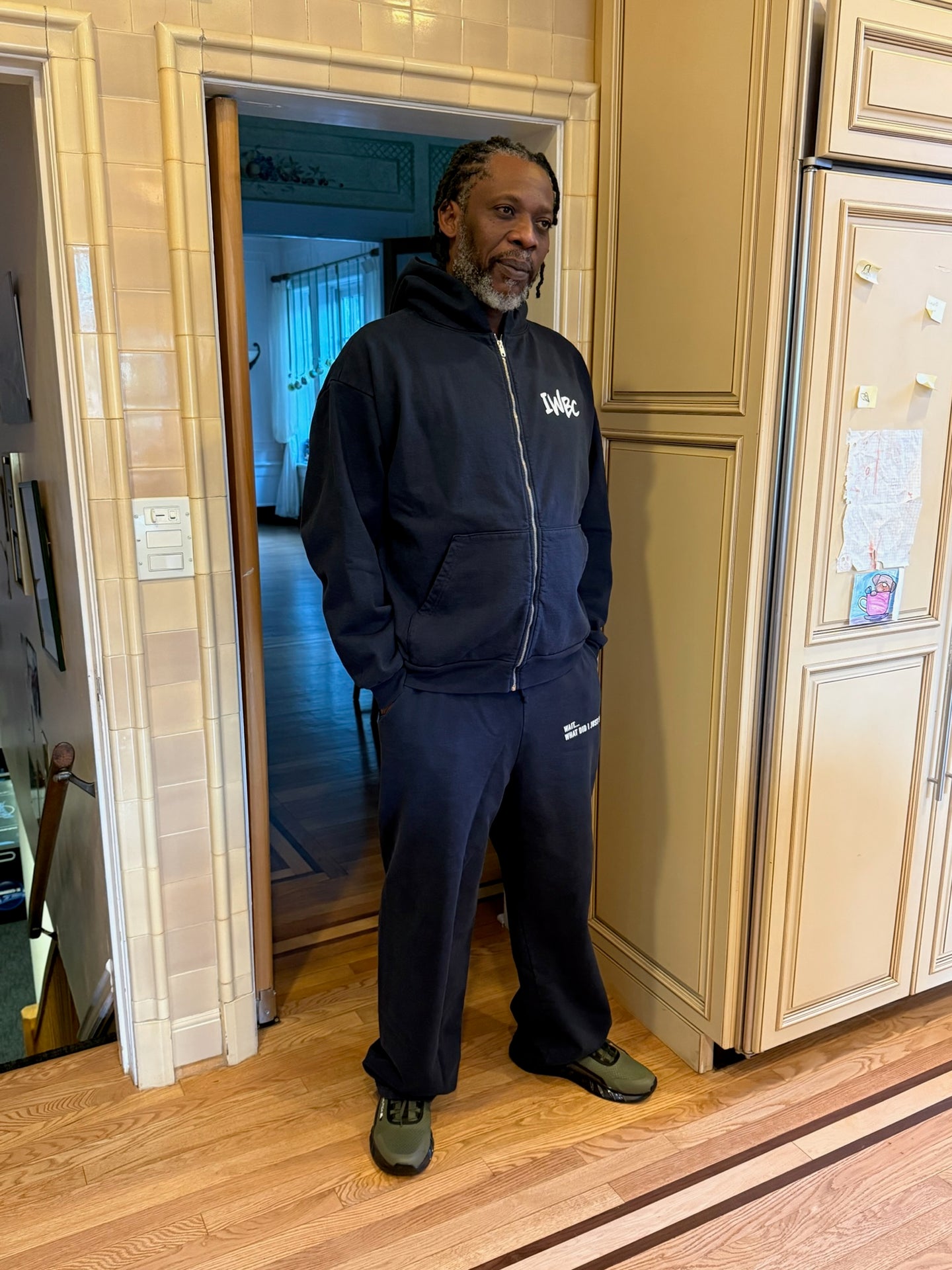 Man in a dark tracksuit standing in a kitchen