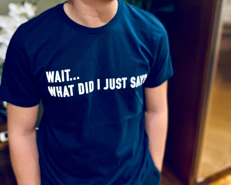 Person wearing a navy blue t-shirt with white text 'WAIT... WHAT DID I JUST SAY?'